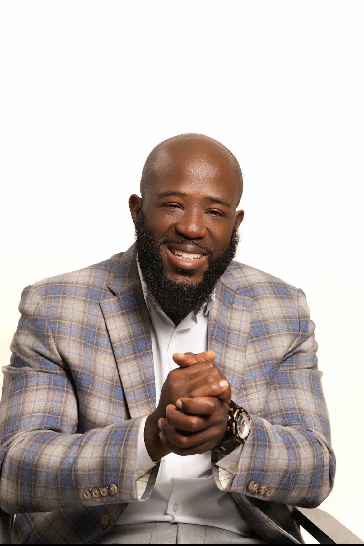 Max Claircius in a checked blazer, hands clasped, direct to camera