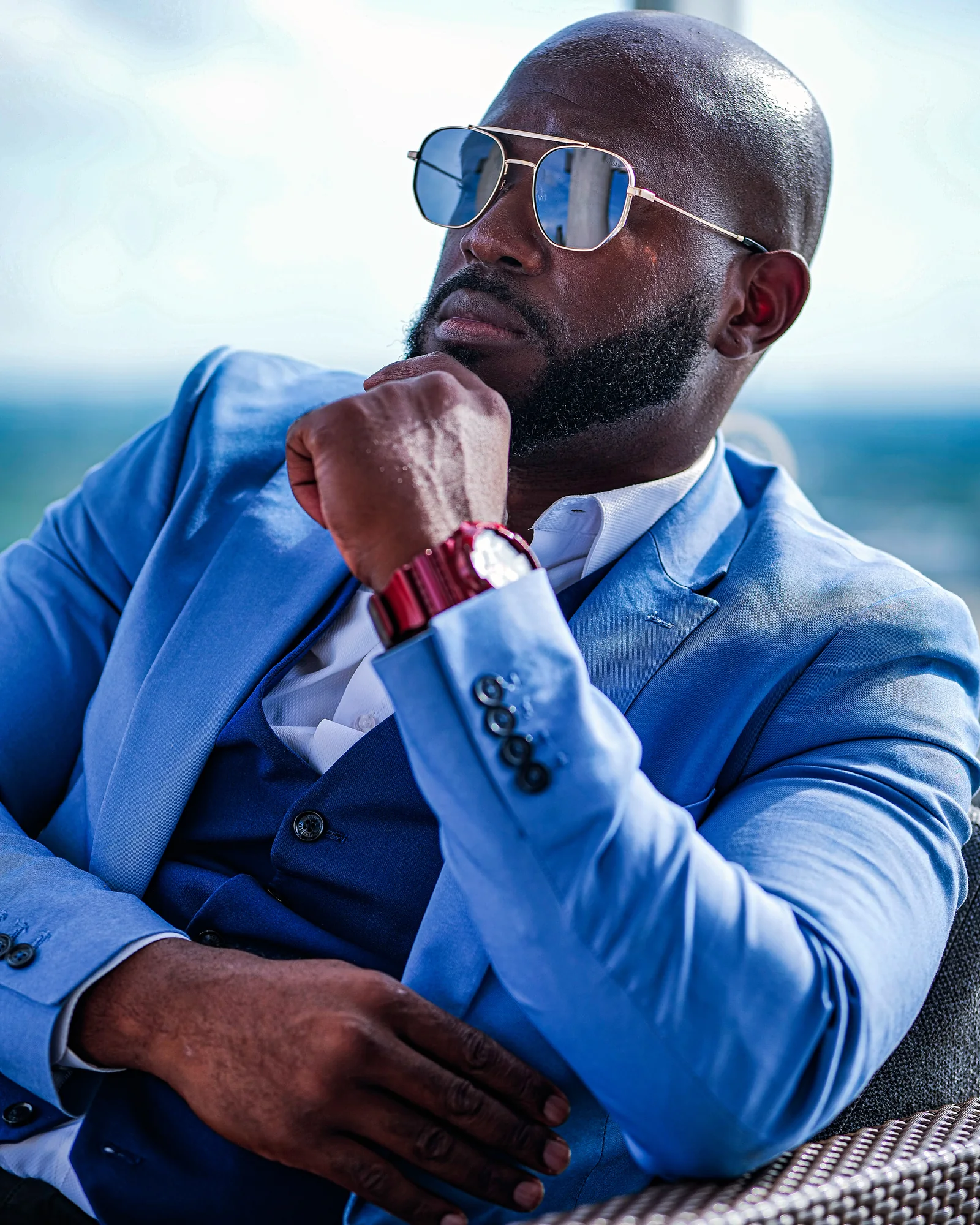 Max Claircius in a cobalt blue three-piece suit, seated in thought